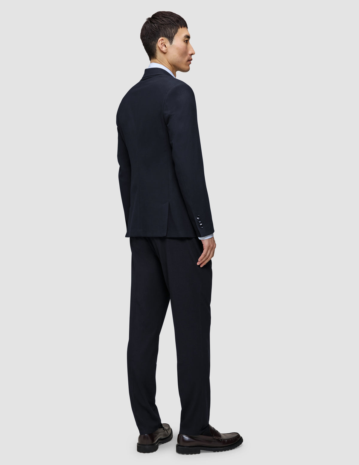 A man seen from behind wearing the navy Motion Blazer Slim Midnight Blue and matching trousers.