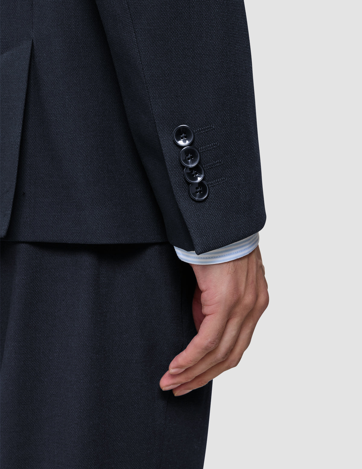 Close-up of a Motion Blazer Slim Midnight Blue sleeve featuring 360° stretch, four cuff buttons, and a white striped shirt sleeve showing underneath.