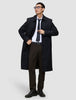 A man wearing a black overcoat, white dress shirt, dark tie, and Motion Suit Pants Regular Cognac.