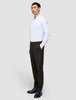 A man stands with his hand in his pocket wearing a white dress shirt and Motion Suit Pants Regular Cognac, which feature 360° stretch.