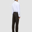 A person viewed from behind, wearing a white button-down shirt and Motion Suit Pants Regular Cognac with black dress shoes.