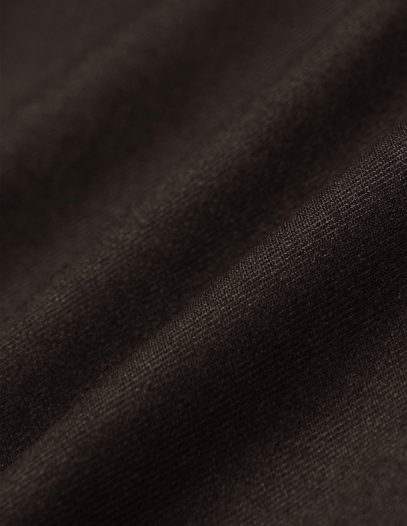 Close-up of the lightweight, breathable brown fabric of the Motion Suit Pants Regular Cognac, shown with soft folds.