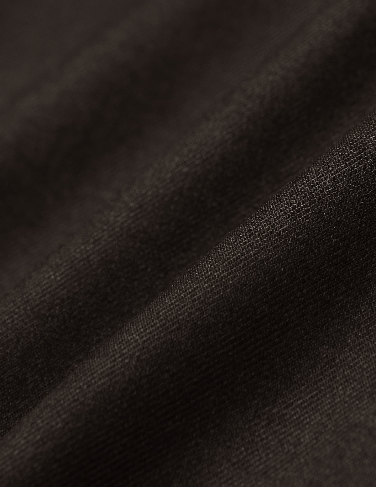 Close-up of the lightweight, breathable brown fabric of the Motion Suit Pants Regular Cognac, shown with soft folds.