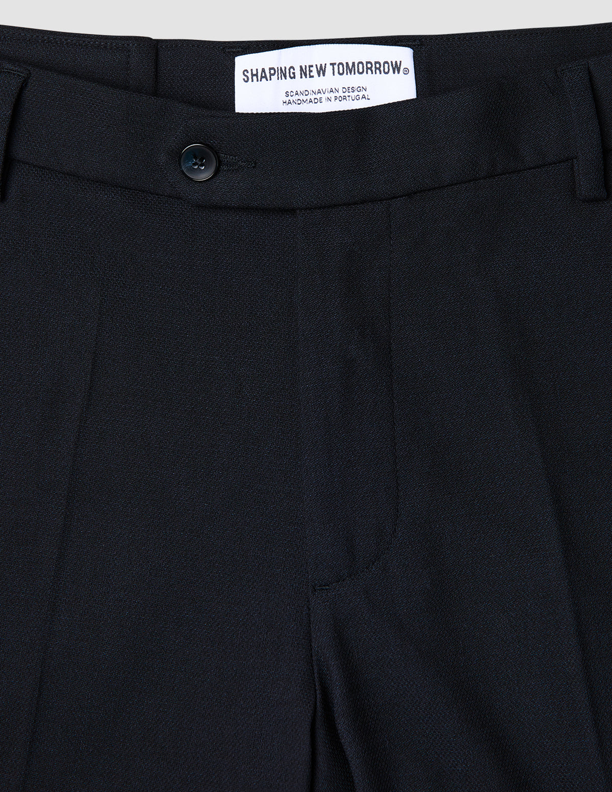Close-up of the waistband and top of Motion Suit Pants Regular Midnight Blue, featuring a button closure and internal brand label on 360° stretch dark blue fabric.