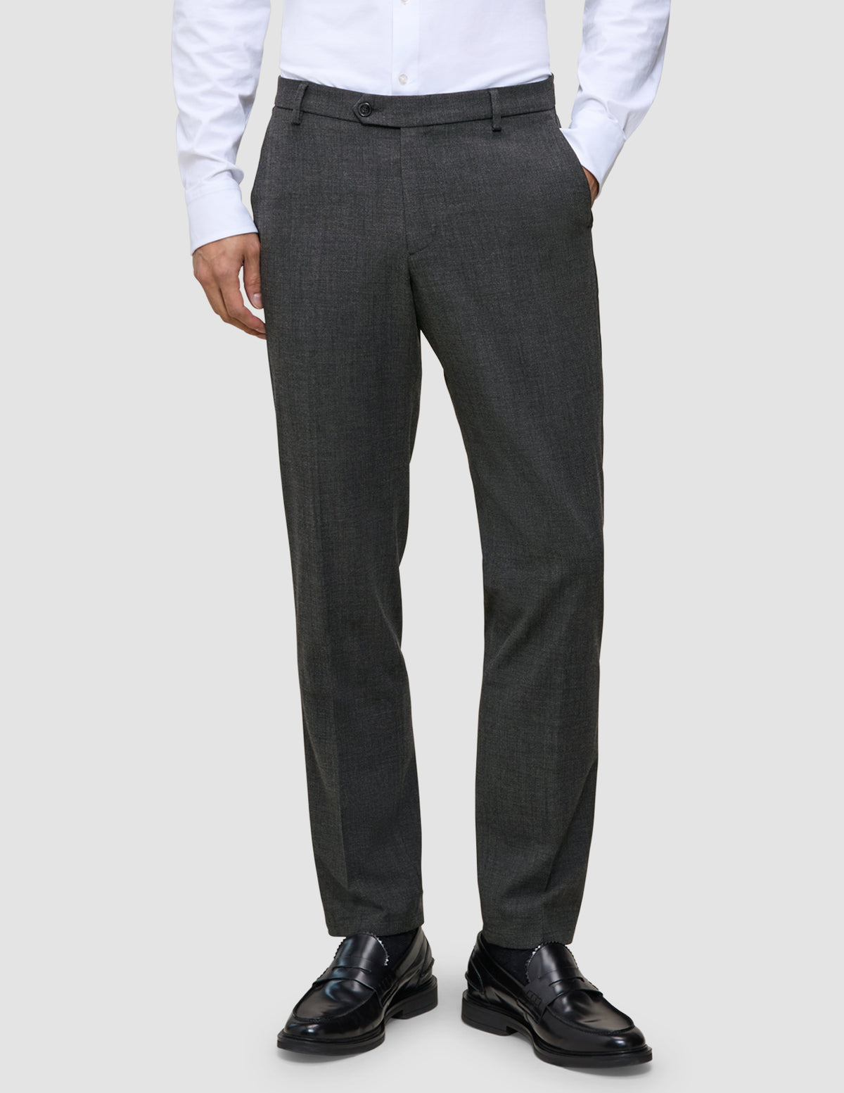A man wearing Motion Suit Pants Regular Pepper Grey, a white button-down shirt, and black loafers.