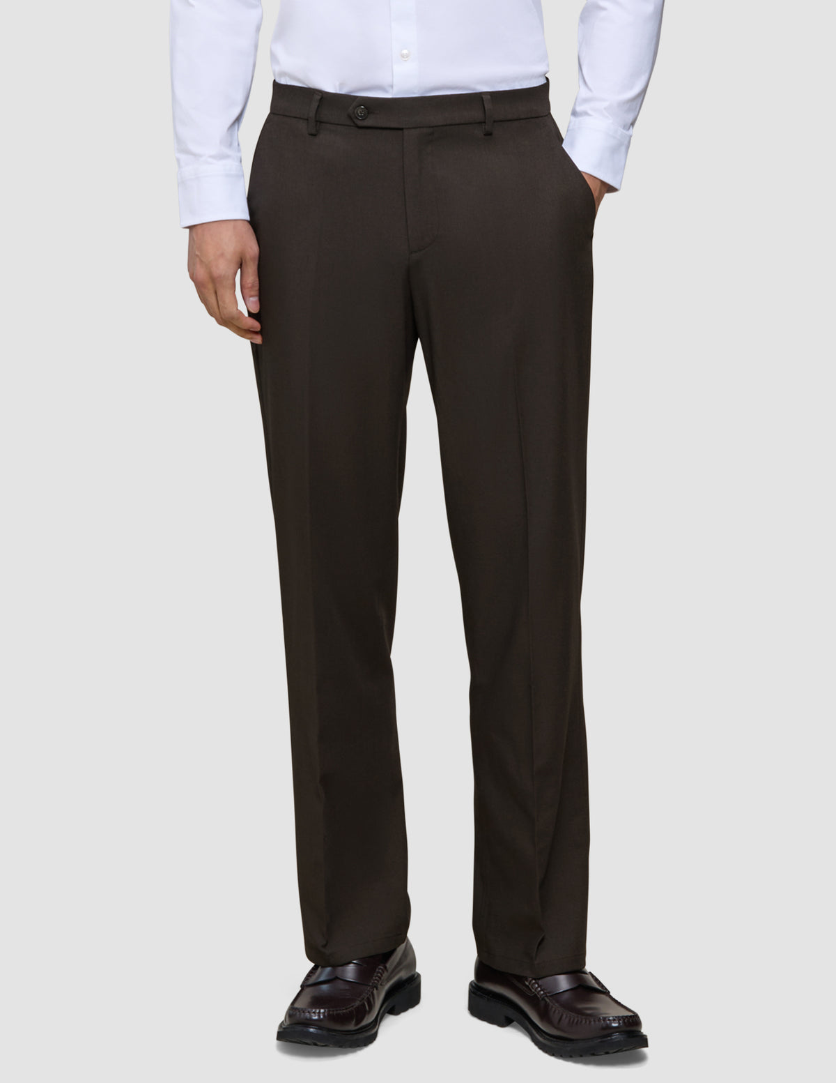 A person wearing a crisp white dress shirt and Motion Suit Pants Relaxed Cognac in a straight-leg fit, paired with dark brown leather loafers.