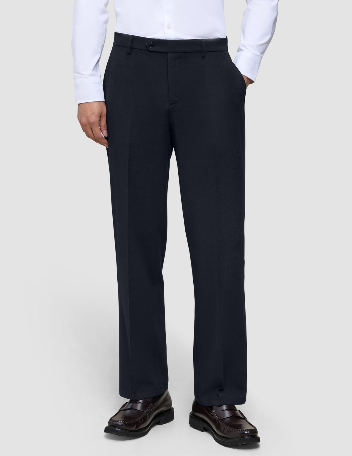A person wearing a white button-down shirt tucked into Motion Suit Pants Relaxed Midnight Blue and brown leather loafers.