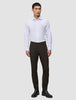 A man wears a white button-down shirt, black leather boots, and slim-fit dark brown Motion Suit Pants Slim Cognac.