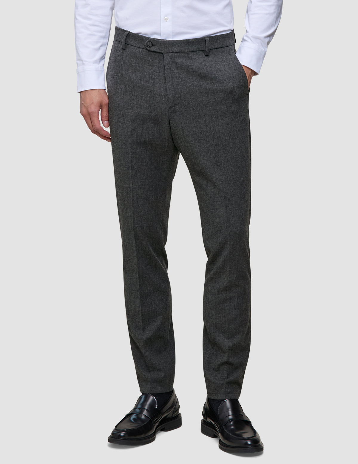 A man wearing a white dress shirt, Motion Suit Pants Slim Pepper Grey, and black loafers.