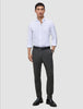 A man wearing a white button-down shirt, a black belt, and Motion Suit Pants Slim Pepper Grey made from breathable charcoal grey fabric.