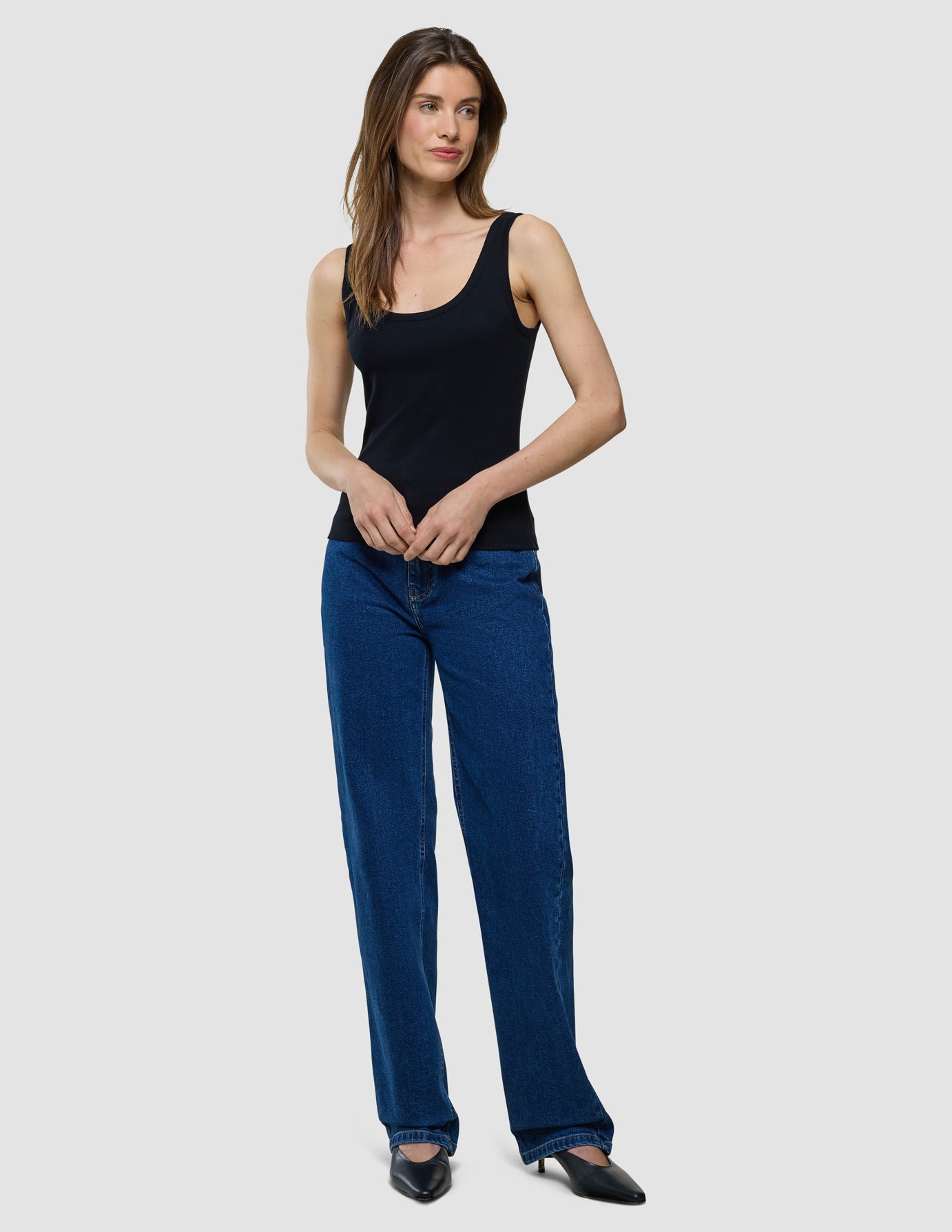 A woman wearing a Rib Tank Top Black and dark blue straight-leg jeans.