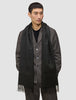 A person wearing a long, fringed Scarf Black over a dark jacket.