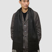 A person wearing a long, fringed Scarf Black over a dark jacket.
