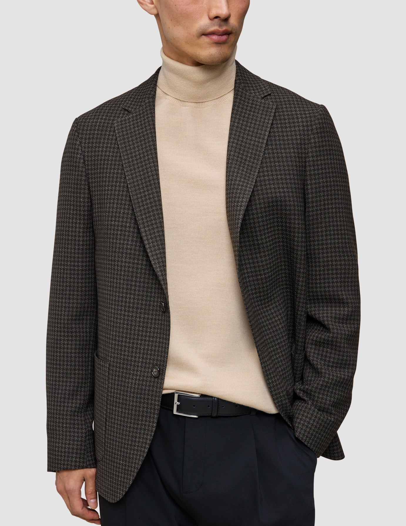 The knit-and-blazer look featuring a person wearing a patterned wool blazer over a merino crewneck sweater and black tech wool pants with a black belt.