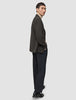 A man wearing a Timeless Wool Blazer Slim Dark Brown Check over a beige turtleneck sweater, paired with dark trousers and black loafers.