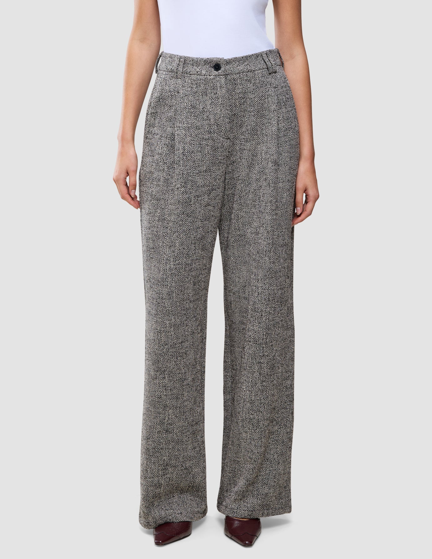 Women Ashryn Pants Wide Domino Herringbone featuring high-waisted, wide-leg trousers in a black and white herringbone bouclé, worn with a white top and dark pointed-toe shoes.