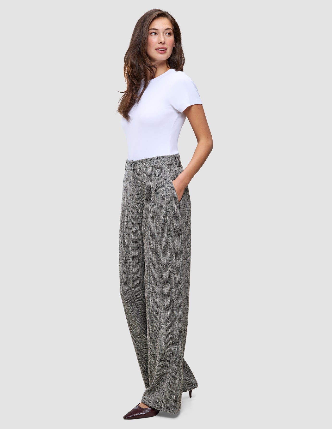 Woman wearing a white t-shirt and grey Women Ashryn Pants Wide Domino Herringbone featuring a high-waisted, wide-leg silhouette.