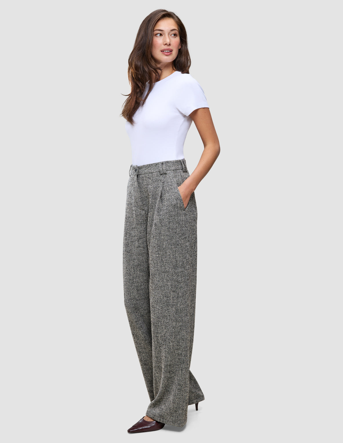 Woman wearing a white t-shirt and grey Women Ashryn Pants Wide Domino Herringbone featuring a high-waisted, wide-leg silhouette.
