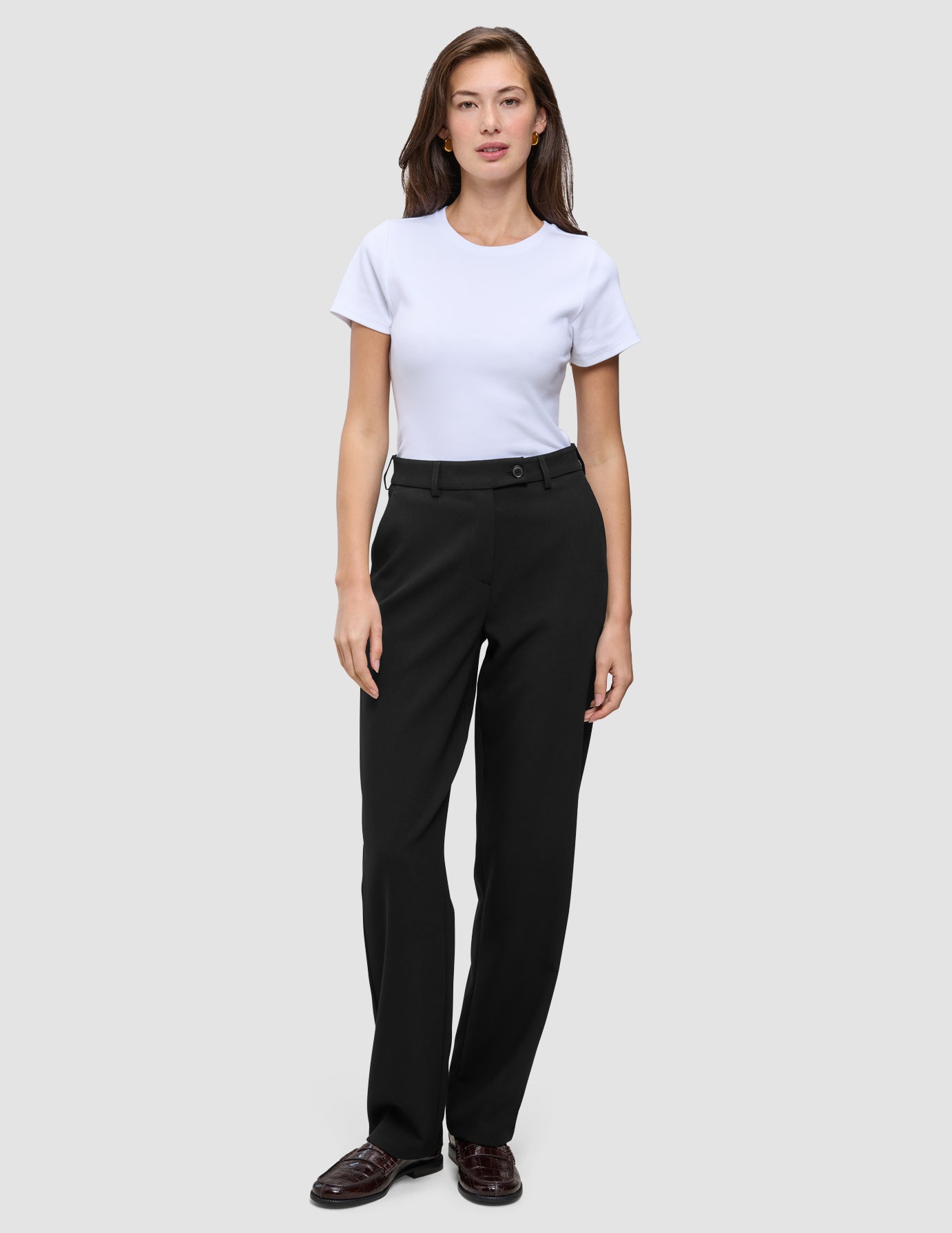 A woman wearing a white t-shirt and Women GO2 Pants Straight Black, which are high-waisted, straight-leg black trousers.