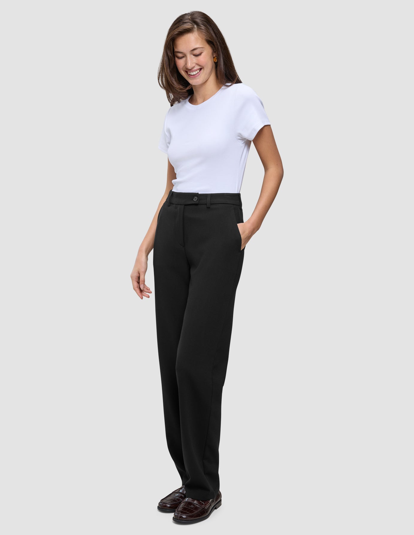 A woman wearing a white t-shirt and Women GO2 Pants Straight Black with her hand in her pocket.