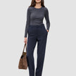A woman wearing a gray long-sleeved shirt and Women GO2 Pants Straight Blue Nights, holding a brown handbag.