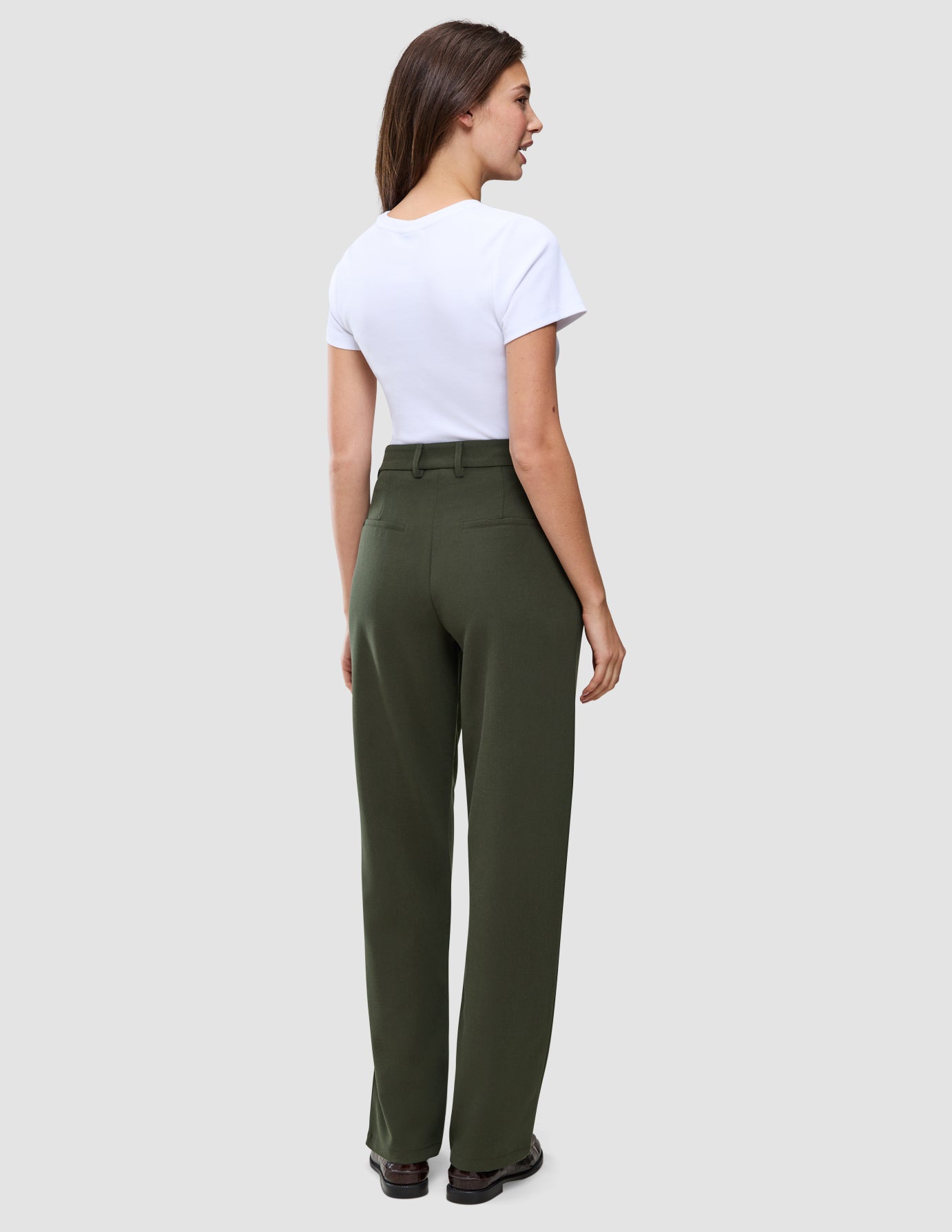 A woman seen from the back wearing a white t-shirt and Women GO2 Pants Straight Dusty Olive.