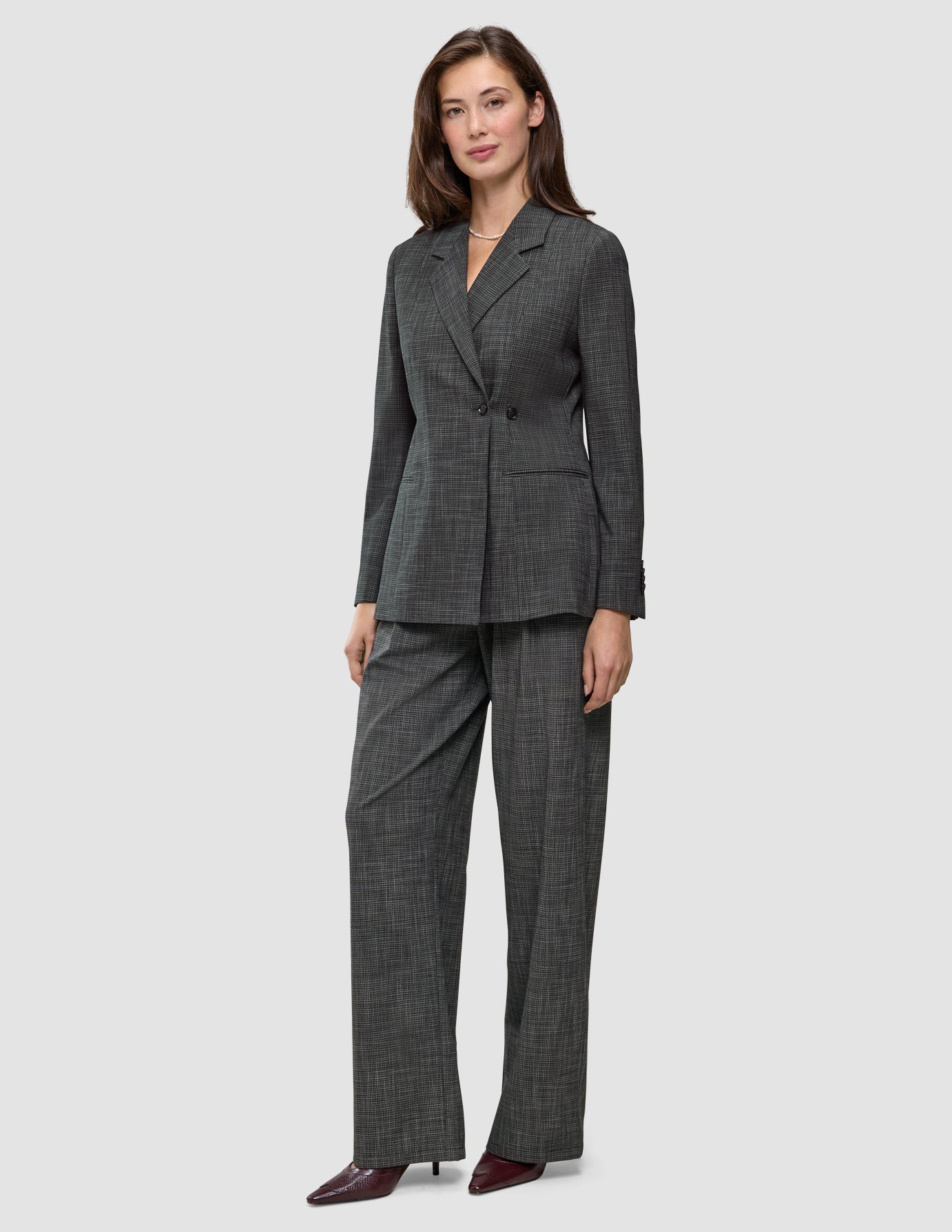 A woman wearing a Women Nara Blazer Fitted Black Check in charcoal gray plaid with matching wide-leg trousers.