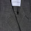 Close-up of a Women Nara Blazer Fitted Black Check, featuring a black and white micro-check pattern and a brand label at the collar.