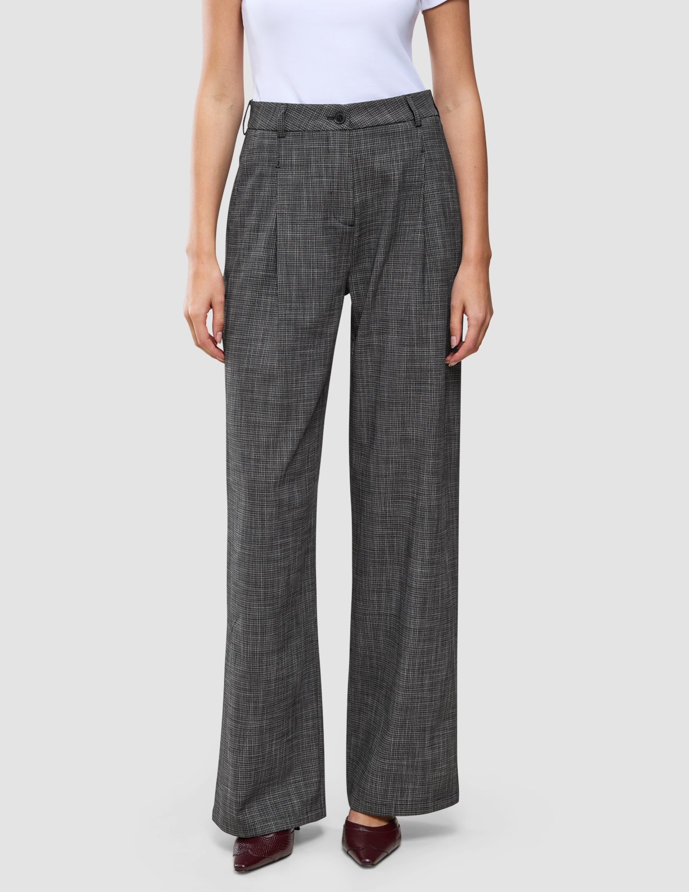 Women Nara Pants Wide Black Check in a dark grey check pattern, worn with a white top and dark pointed-toe shoes.