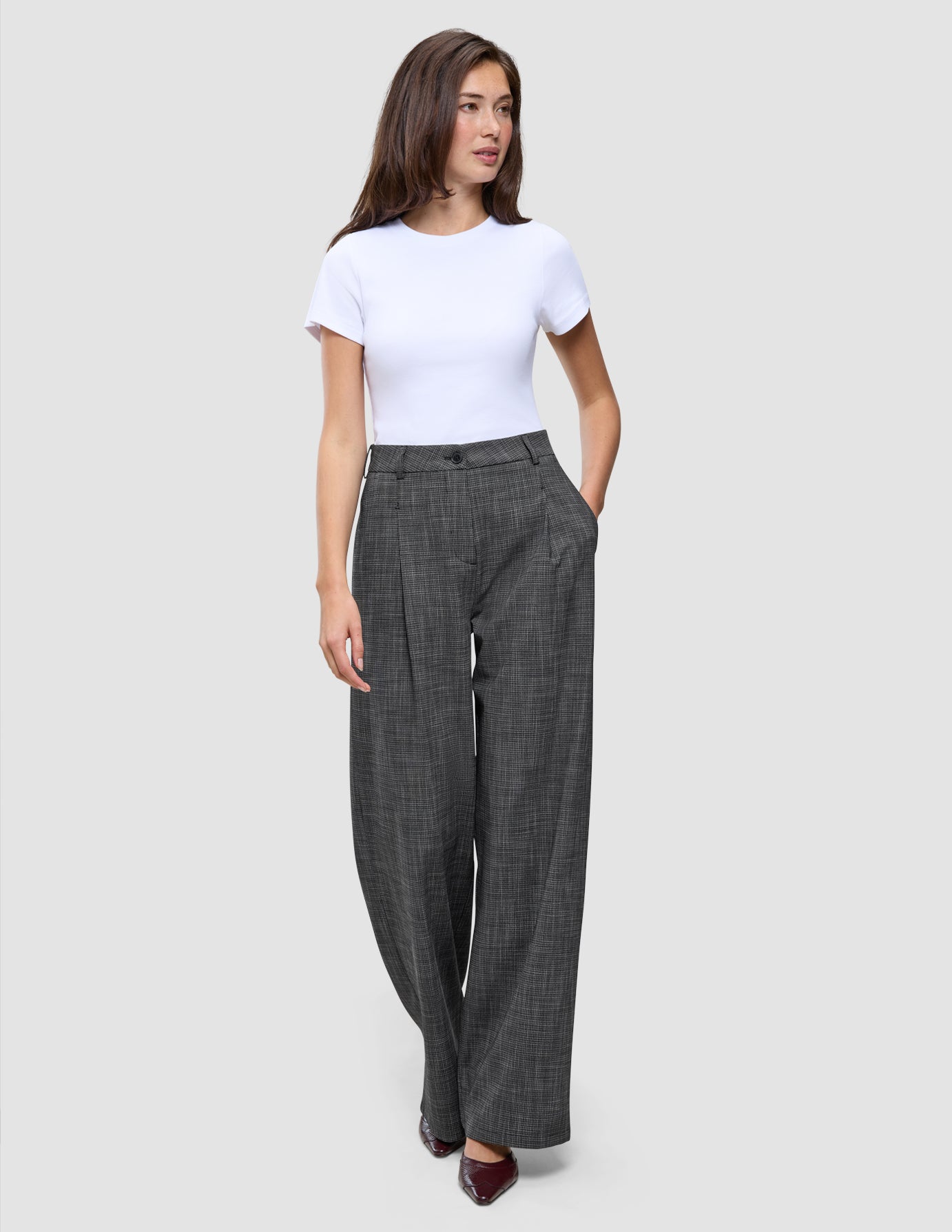 A woman wearing a white t-shirt and high-waisted, black and white Women Nara Pants Wide Black Check.