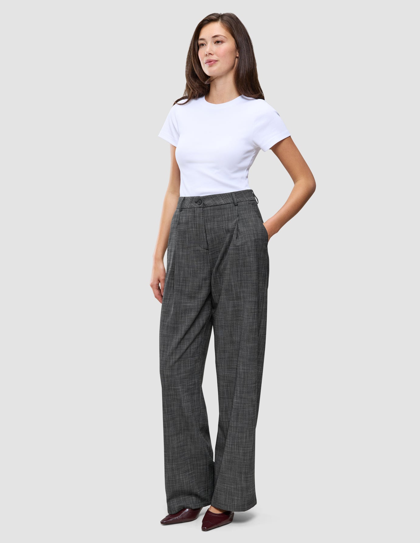 A woman wearing a white t-shirt and Women Nara Pants Wide Black Check with one hand in her pocket.