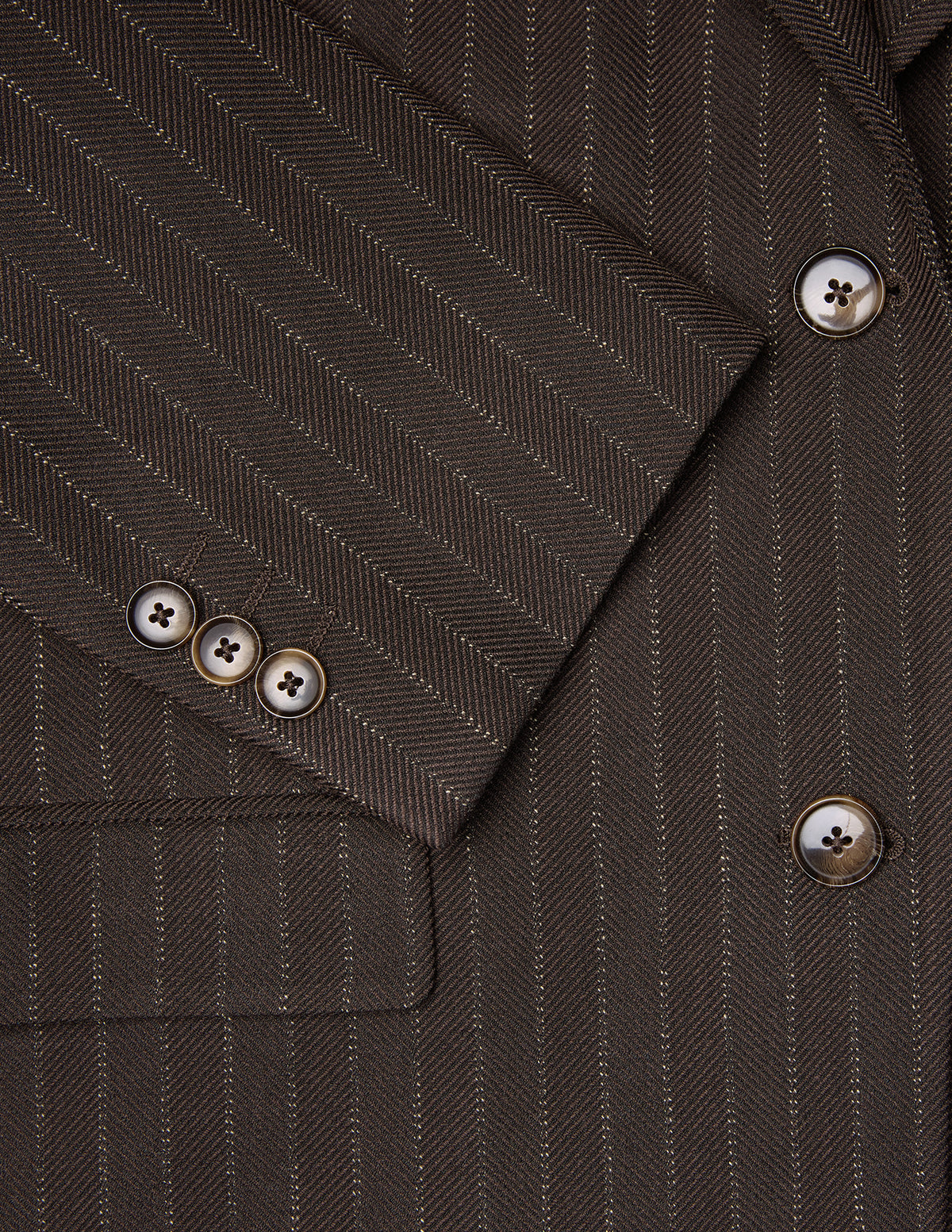 Close-up of a Women Serene Blazer Regular Walnut Herringbone featuring a brown herringbone wool pattern with vertical pinstripes and tortoiseshell buttons on the cuff and front.