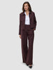 A woman wears a dark pinstriped Women Serene Pants Wide Berry Pinstripe blazer and matching wool-like wide-leg trousers over a white collared shirt.