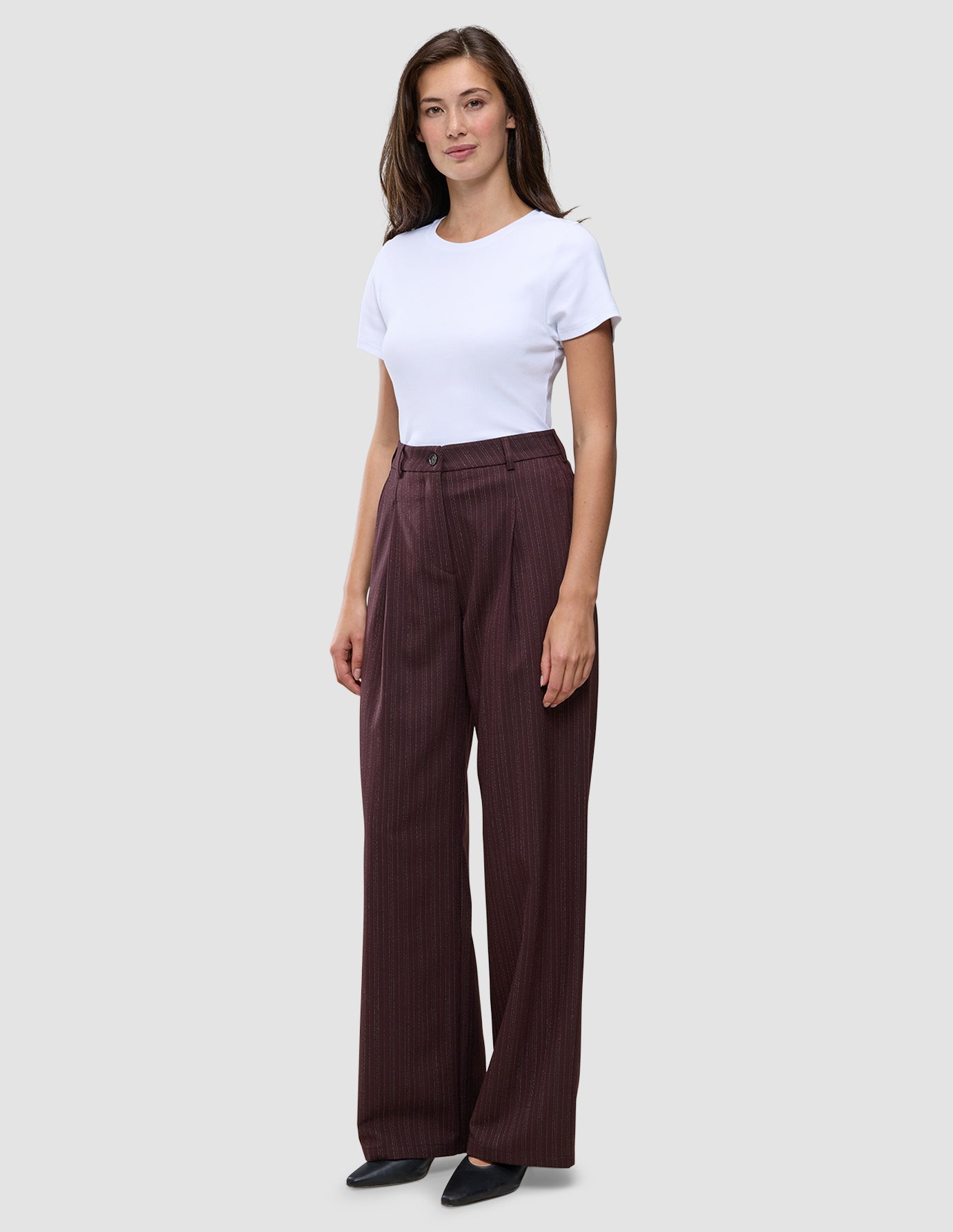 A woman wears a white t-shirt tucked into Women Serene Pants Wide Berry Pinstripe.