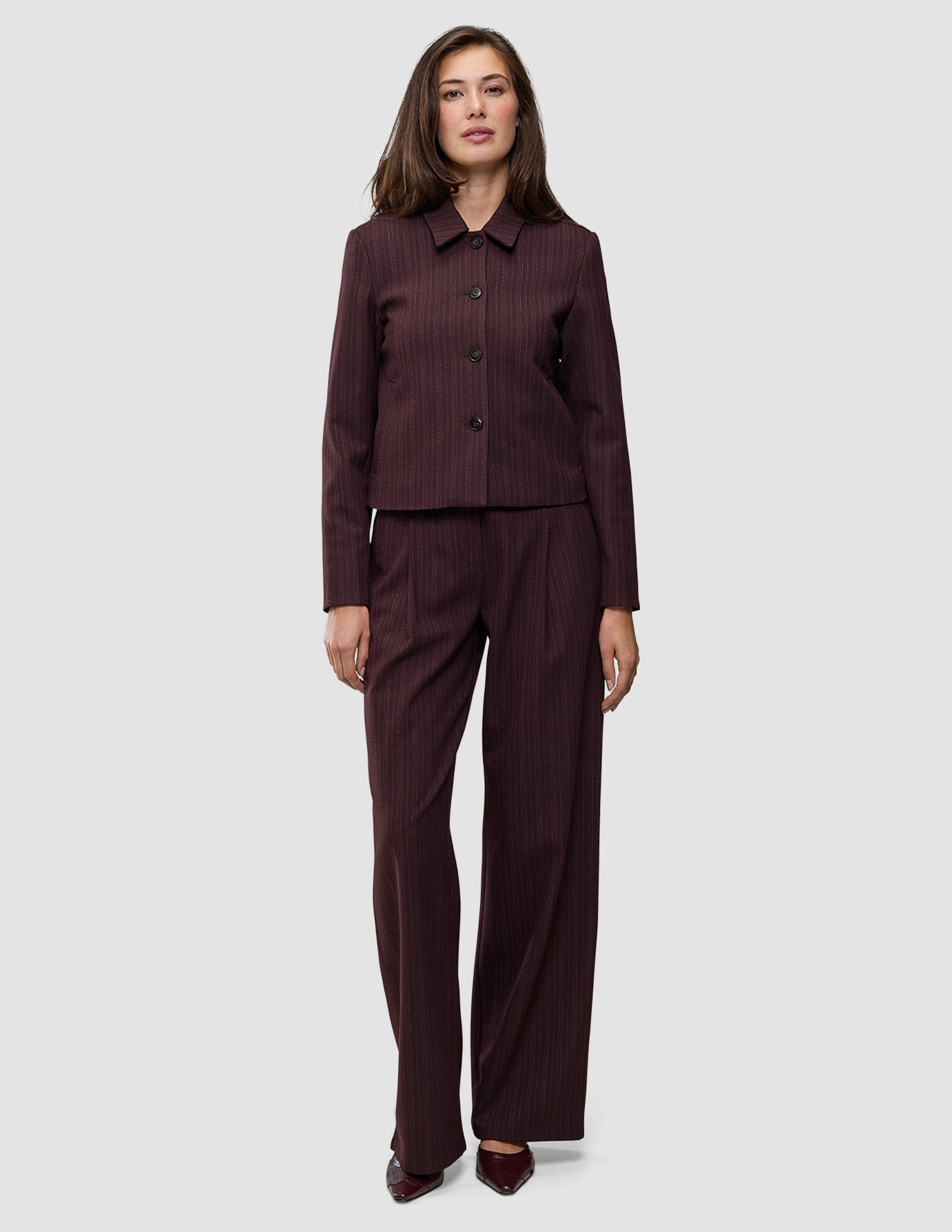 A woman wearing a Women Serene Short Jacket Berry Pinstripe with matching wide-leg trousers in a Scandinavian design.