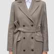 Women Wool Coat Greige in a double-breasted Scandinavian design, featuring a tie waist and flap pockets worn over a white collared shirt.