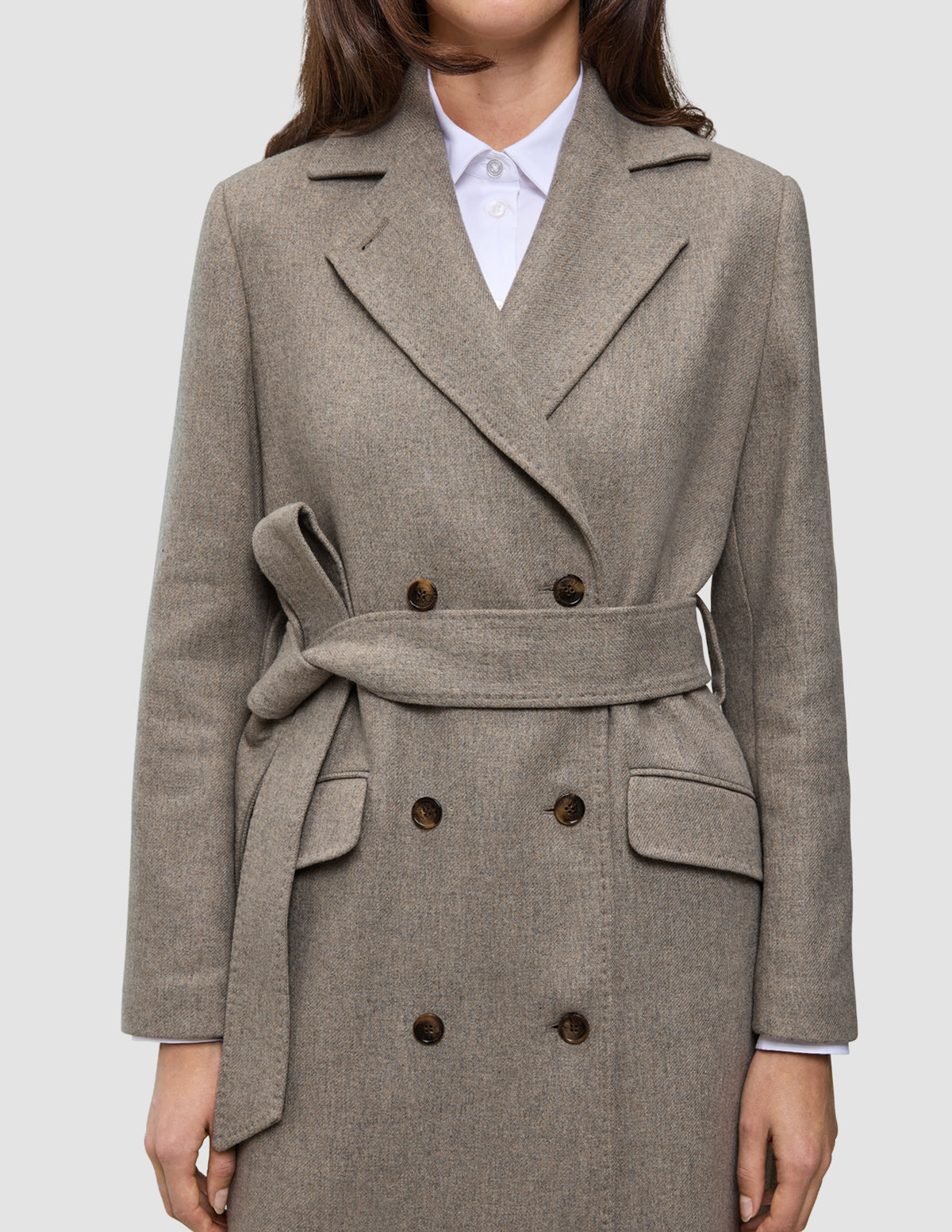 Women Wool Coat Greige in a double-breasted Scandinavian design, featuring a tie waist and flap pockets worn over a white collared shirt.