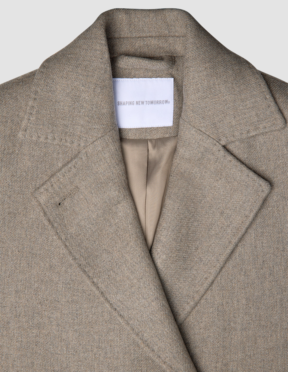 Close-up of a Women Wool Coat Greige, featuring a double-breasted design with wide lapels and a brand label at the neckline.