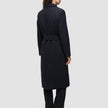 A woman viewed from the back wearing a Women’s Wool Coat Black, featuring a long Scandinavian design with a belted waist.